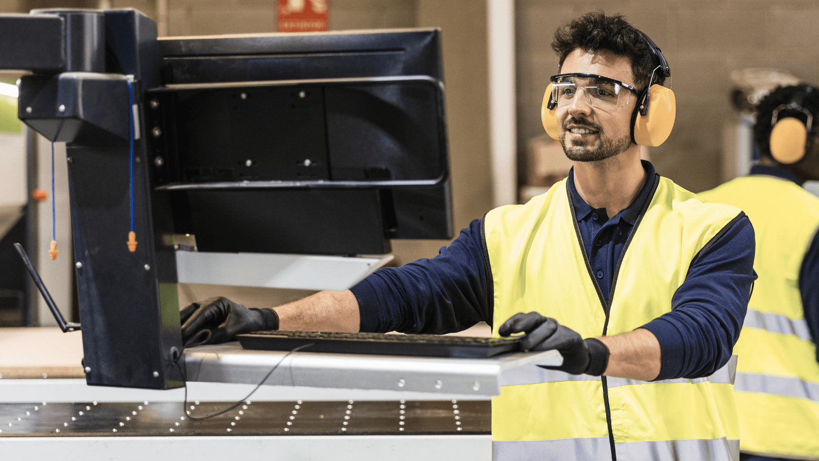 CNC tezgah işçisi tarafından kontrol paneli üzerinden endüstriyel üretim hattının yönetilmesi süreci