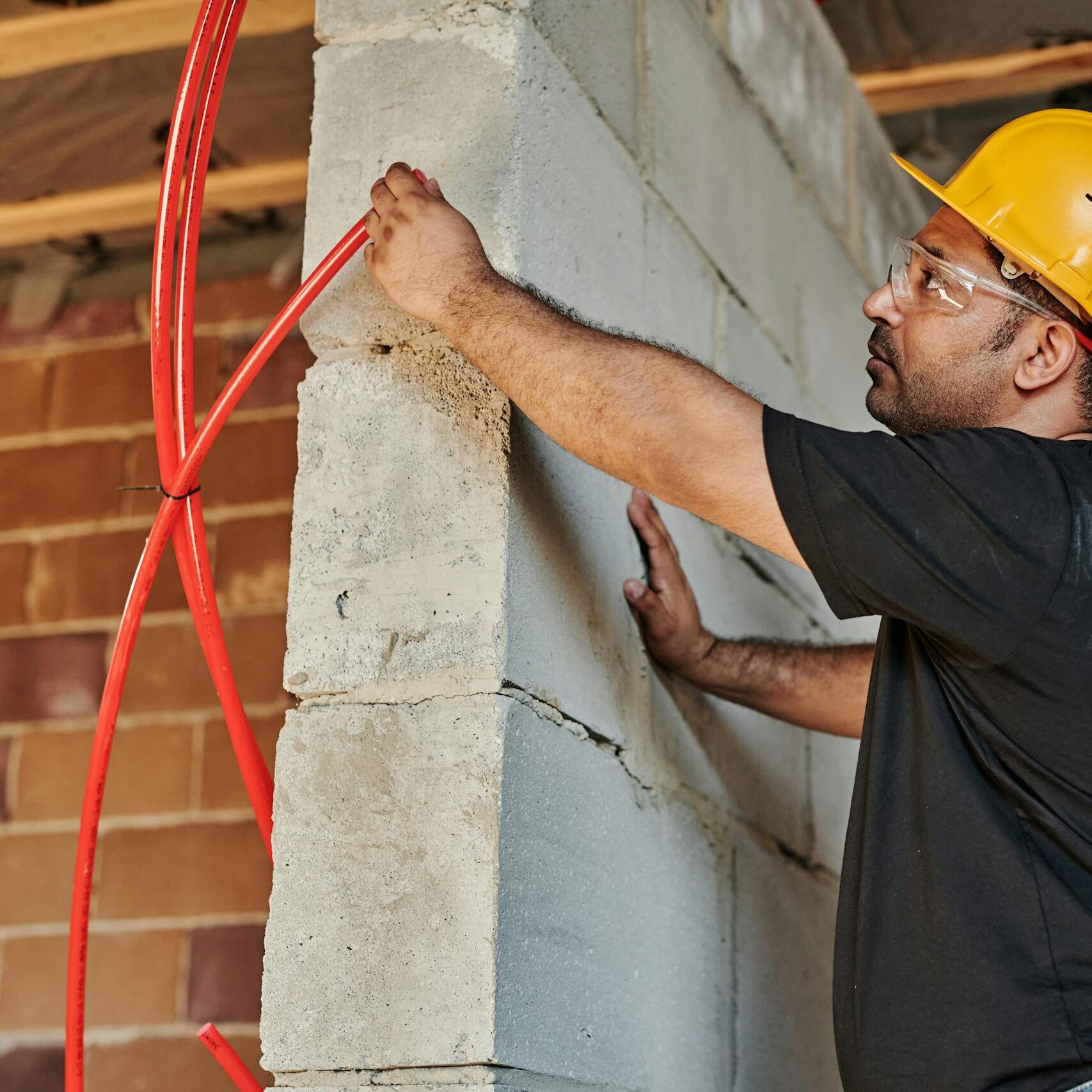 Şantiye ortamında bareti ve koruyucu ekipmanıyla bina içi elektrik kablo montajı yapan elektrik teknisyeni